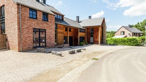 Una moderna casa in mattoni con un ampio vialetto e una zona esterna coperta.