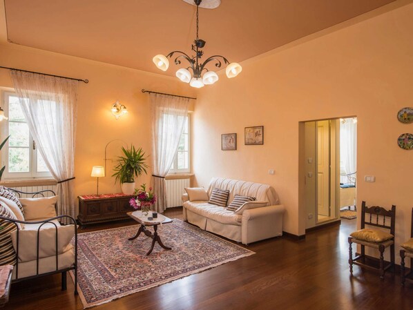 Un salon chaleureux avec un canapé, des fauteuils, une table basse et un lustre.