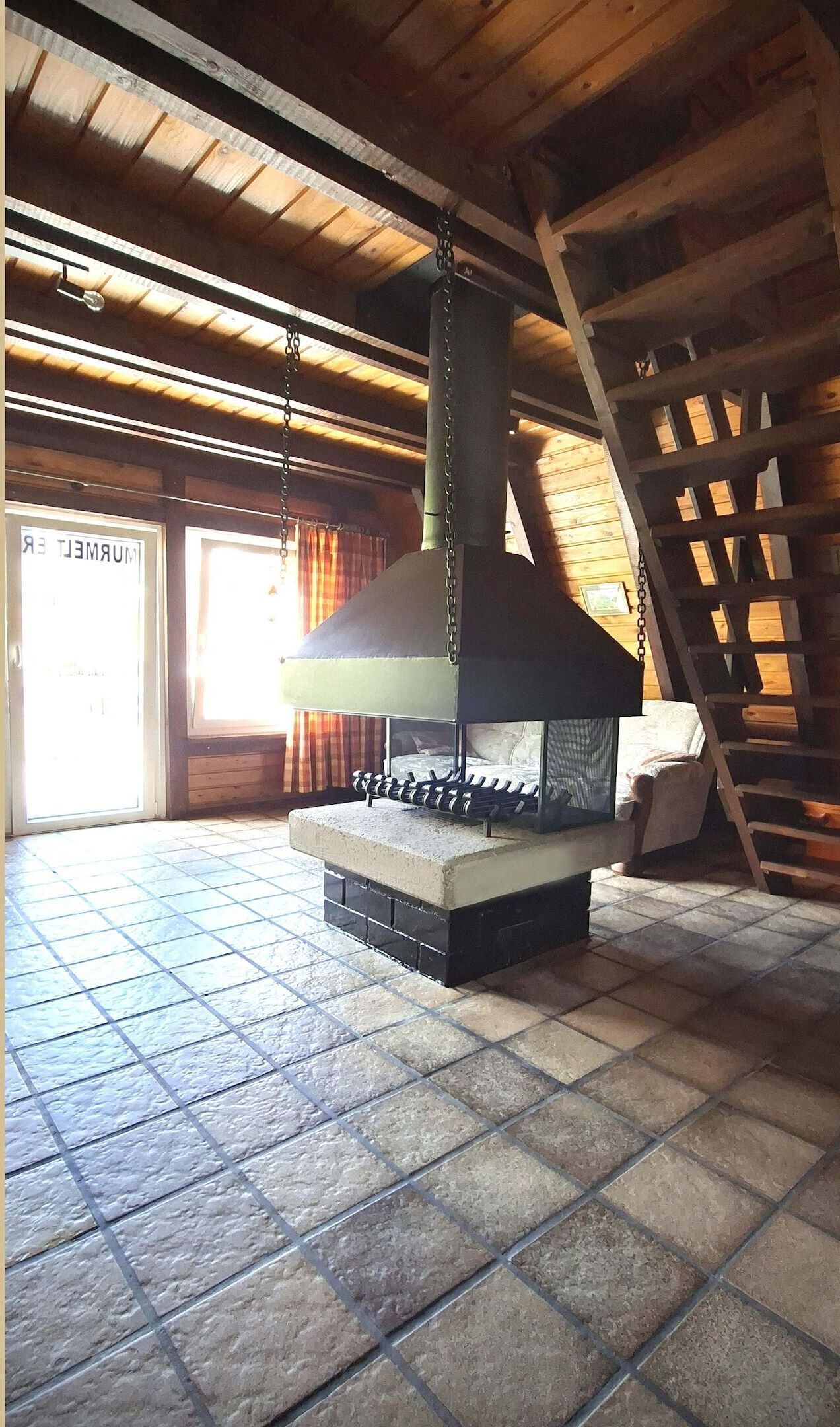 Un sol carrelé de pierres, une grande cheminée et un plafond en bois.