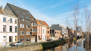 A canal-side street with multi-story buildings, a bicycle path, and parked cars. - House in Zingem Near Hiking Trails (Kruishoutem)