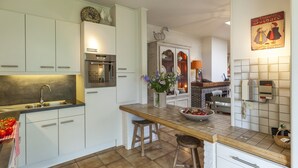 A modern kitchen with white cabinets, a built-in oven, a sink, and a tiled backsplash. - House in Zingem Near Hiking Trails (Kruishoutem)