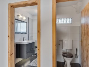 A modern bathroom with a toilet, sink, and mirror. - Voluminous Apartment near Ski Slopes in Maria Alm (Maria Alm am Steinernen Meer)