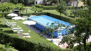 A swimming pool surrounded by a well-maintained lawn, with lounge chairs and umbrellas. - Rural Retreat in Sassoleone (Casalfiumanese)