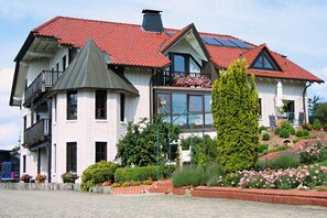 A two-story house with a red-tiled roof, a turret, and a balcony.