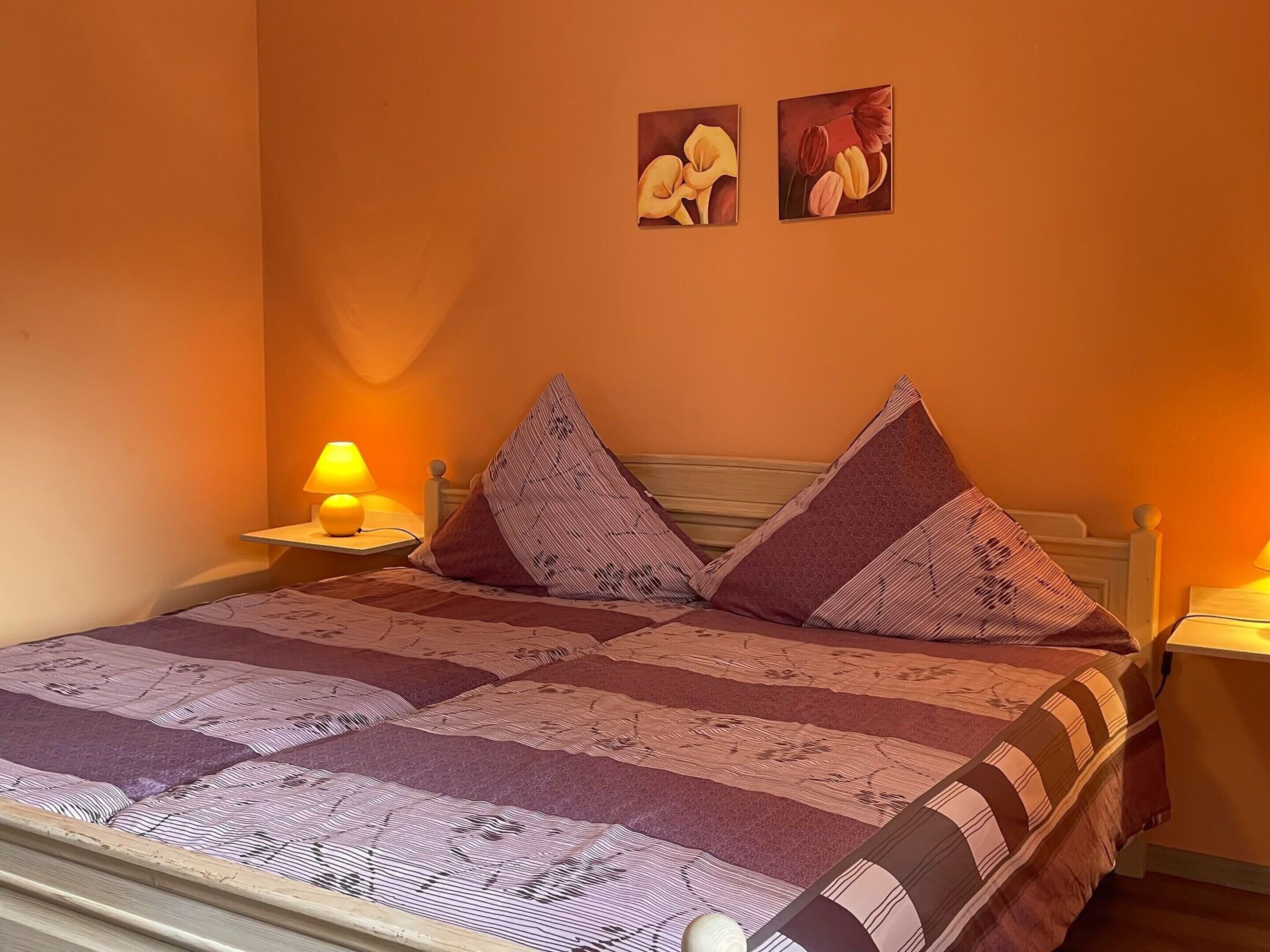 Un lit avec une couverture à rayures, deux oreillers et deux tableaux accrochés au mur.