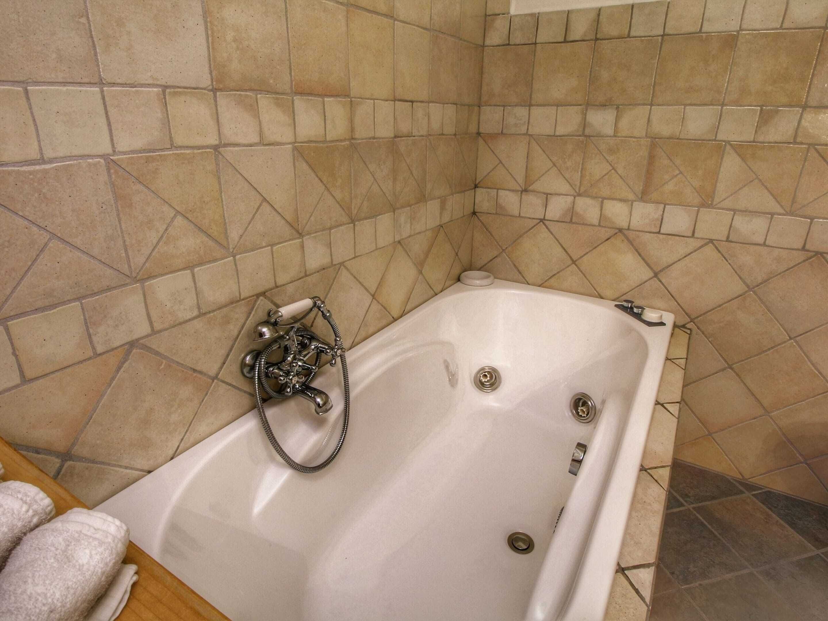 Ein Badezimmer mit Badewanne, Duschbrause und gefliesten Wänden.