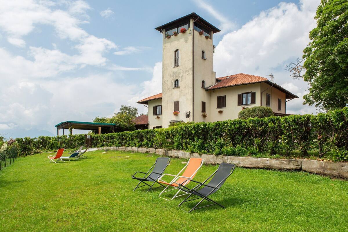 A large house with a tower, a grassy lawn, and two lounge chairs.
