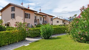 A row of residential buildings with a well-maintained lawn and hedges. - Holiday Home in Bardolino With Pool & Lake Views (Bardolino)