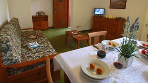 A cozy living room with a sofa, a dining table set with plates, a wine glass, and a TV. - Seaside Escape in Giannella (Orbetello)
