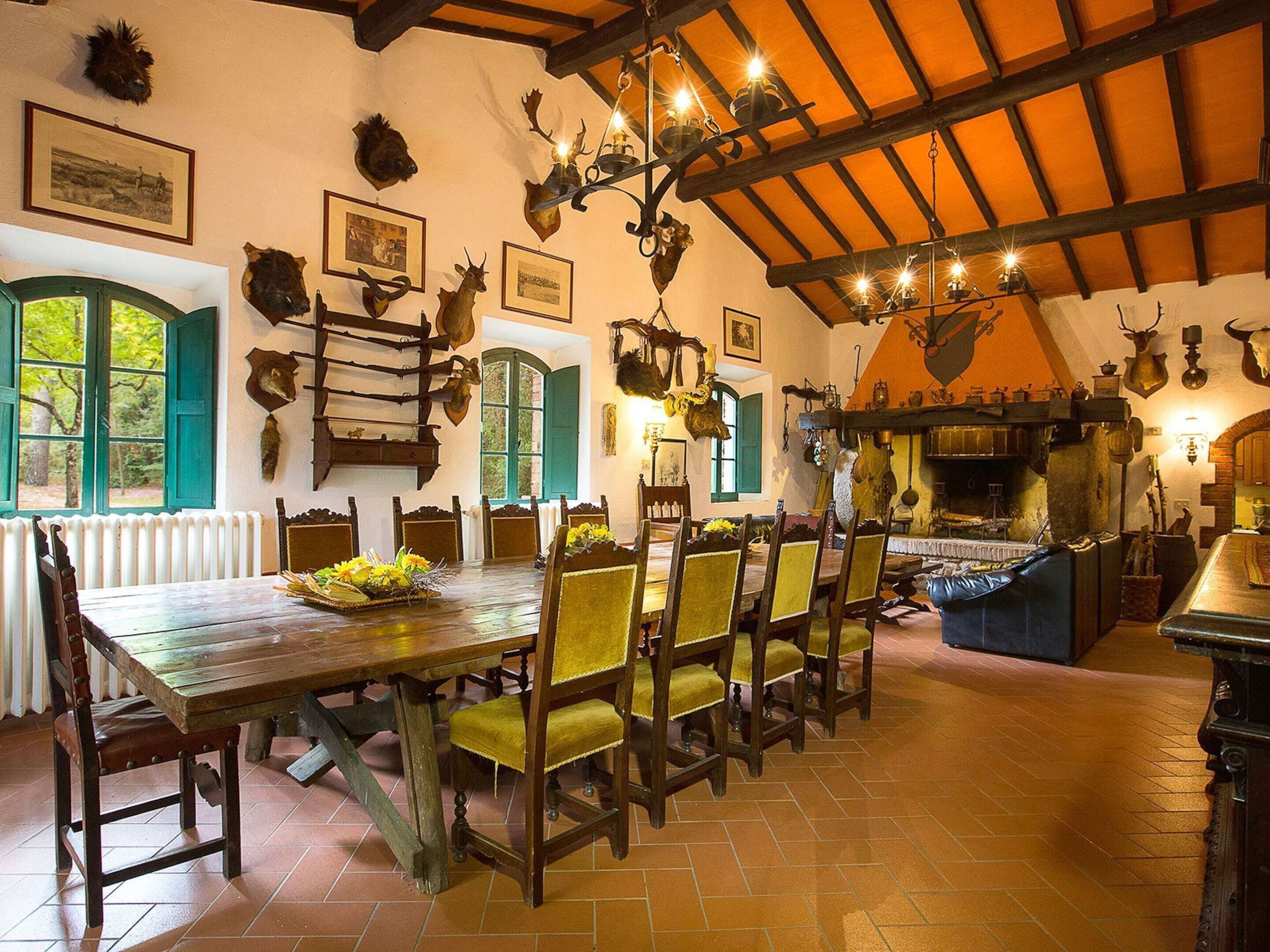 A rustic dining area with a long wooden table, several chairs, and a fireplace.