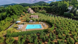 An aerial view of a resort with a swimming pool surrounded by lush greenery and a small building. - Farmhouse Montepulciano Near Vineyards Pool (Montepulciano)