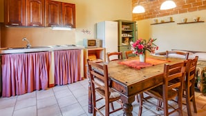 Une cuisine dotée de meubles en bois, d’un four à micro-ondes encastré et d’un coin repas avec une table et des chaises en bois.