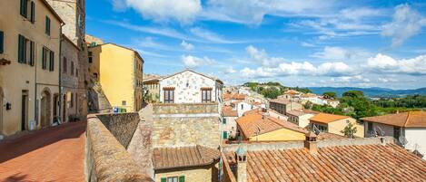 Un pueblo histórico con edificios de piedra, una torre destacada y una calle adoquinada.