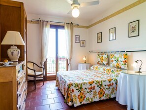 A bedroom with a bed, a chair, a dresser, a table, and a ceiling fan. - Belvilla by OYO Villa Conte (Ricadi)