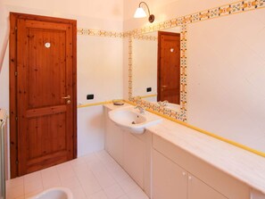 A bathroom with a wooden door, a sink, and a mirror. - Belvilla by OYO Villa Conte (Ricadi)