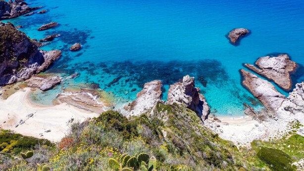 A coastal landscape with rocky formations, clear blue waters, and a sandy beach. - Belvilla by OYO Villa Conte (Ricadi)