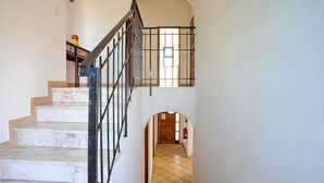 Un escalier en marbre, avec une rampe en métal noir, mène à une porte en bois située en haut.