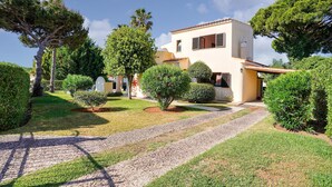 Une maison à deux étages avec une allée pavée, entourée de pelouses et d’arbres bien entretenus.