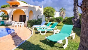 Un espace piscine avec des chaises longues et un bâtiment orné d’arches.