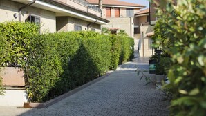Een verhard pad langs keurig gesnoeide hagen en gebouwen met balkons.