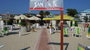 Een restaurant aan het strand genaamd 'Arrivederci' met terras en parasols.