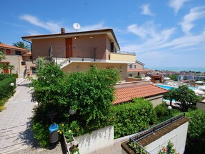 Une maison à deux étages avec un balcon, une piscine et une vue sur la mer.