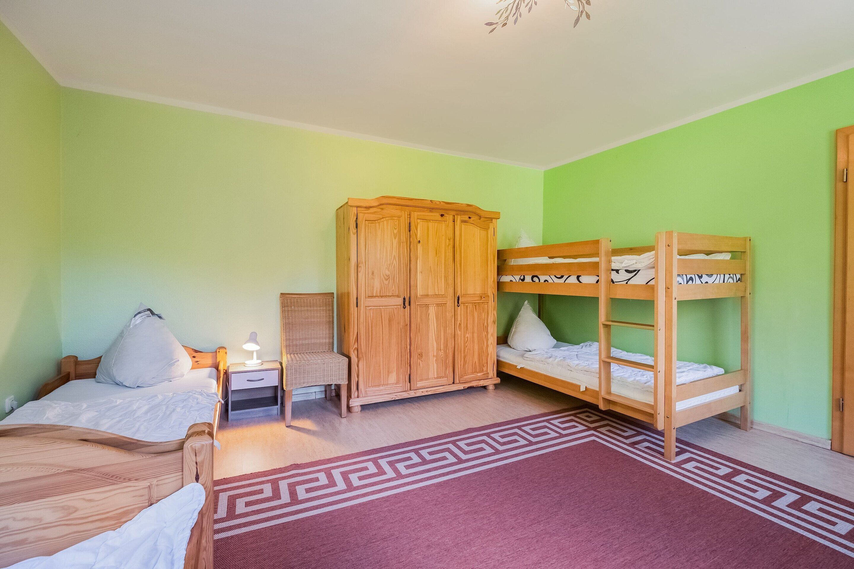 Une chambre avec deux lits en bois, une armoire, une table de chevet et un tapis à motifs.