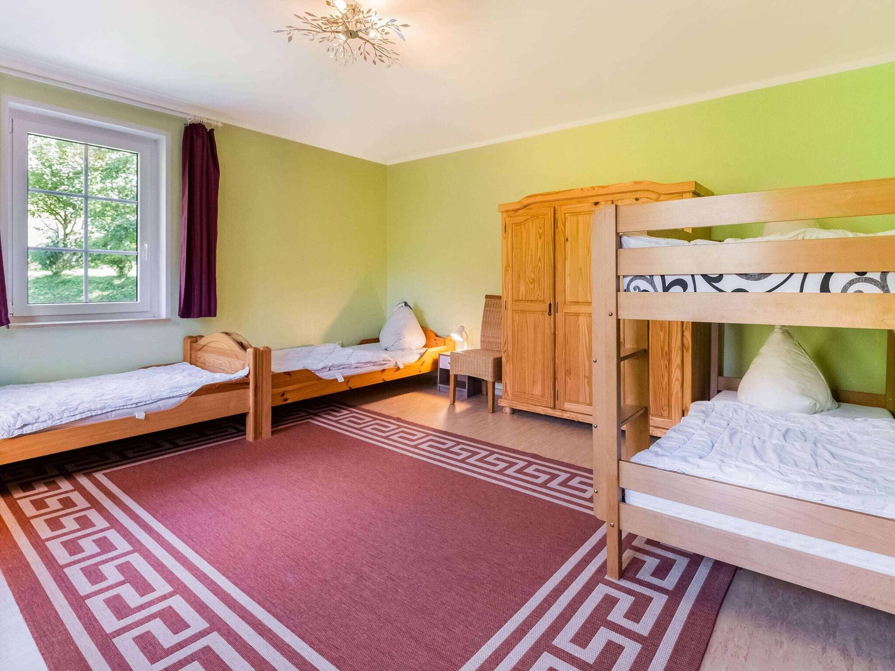 Une chambre de dortoir avec deux lits simples, une armoire en bois, un bureau et une chaise.