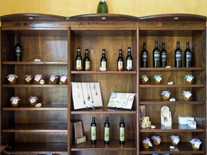Un porte-bouteilles en bois, doté de plusieurs étagères où sont rangées des bouteilles et des bocaux, dont certains sont munis d’étiquettes indiquant leur prix.