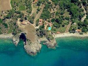 An aerial view of a coastal property with a rocky shoreline, a swimming pool, and a small building. - Mansion in Capo Vaticano With Sea Views (Ricadi)