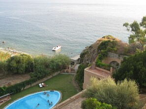 A swimming pool with people, a boat on the water, and a view of the sea. - Mansion in Capo Vaticano With Sea Views (Ricadi)