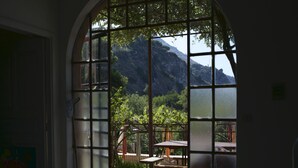 A room with a large arched window overlooking a patio area with outdoor furniture and a view of a mountainous landscape. - Mansion in Capo Vaticano With Sea Views (Ricadi)