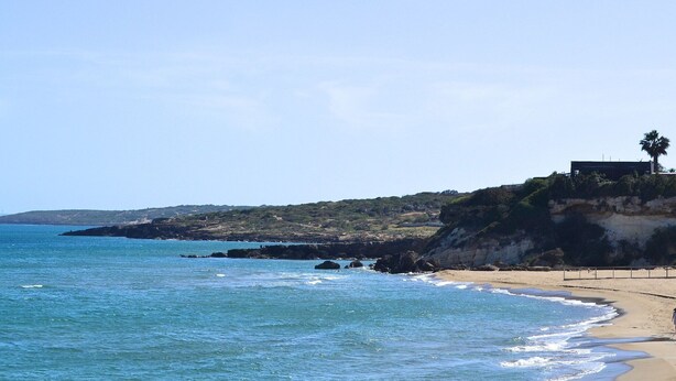 A coastal landscape with a beach, rocky cliffs, and a palm tree. - Holiday Home in Lido di Noto Near Beach (Noto)