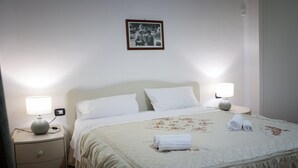 A neatly made bed with white linens, two bedside lamps, and a framed picture on the wall. - Holiday Home in Lido di Noto Near Beach (Noto)