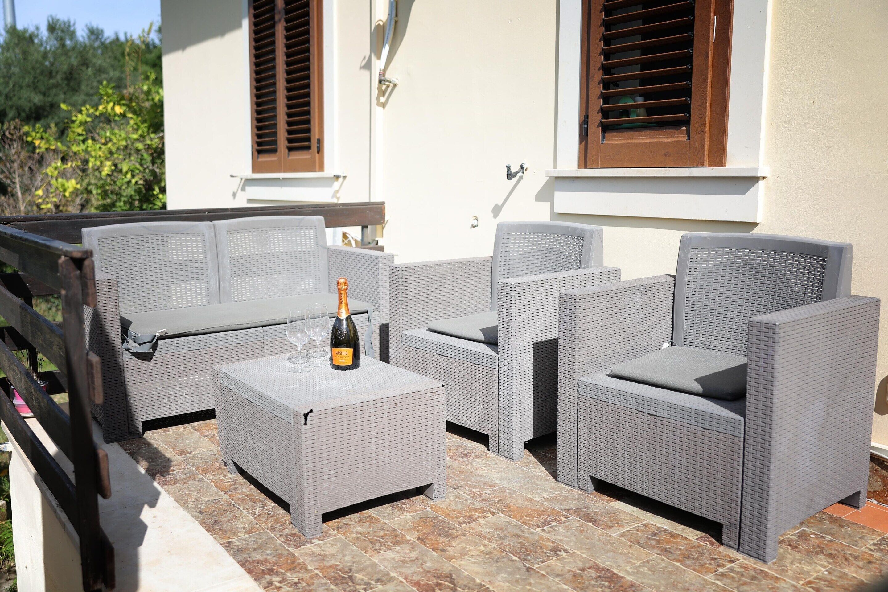 Eine Terrasse mit Korbmöbeln, einer Champagnerflasche und einem Fliesenboden.