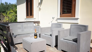 A patio with wicker furniture, a bottle of champagne, and a tiled floor. - Holiday Home in Lido di Noto Near Beach (Noto)
