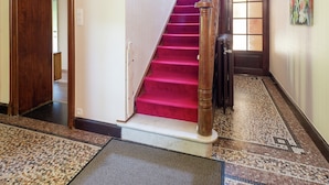 A staircase with red carpet and wooden balusters, leading to a room with a tiled floor and a doormat. - Captivating Holiday Home in Malmedy With Sauna (Malmedy)