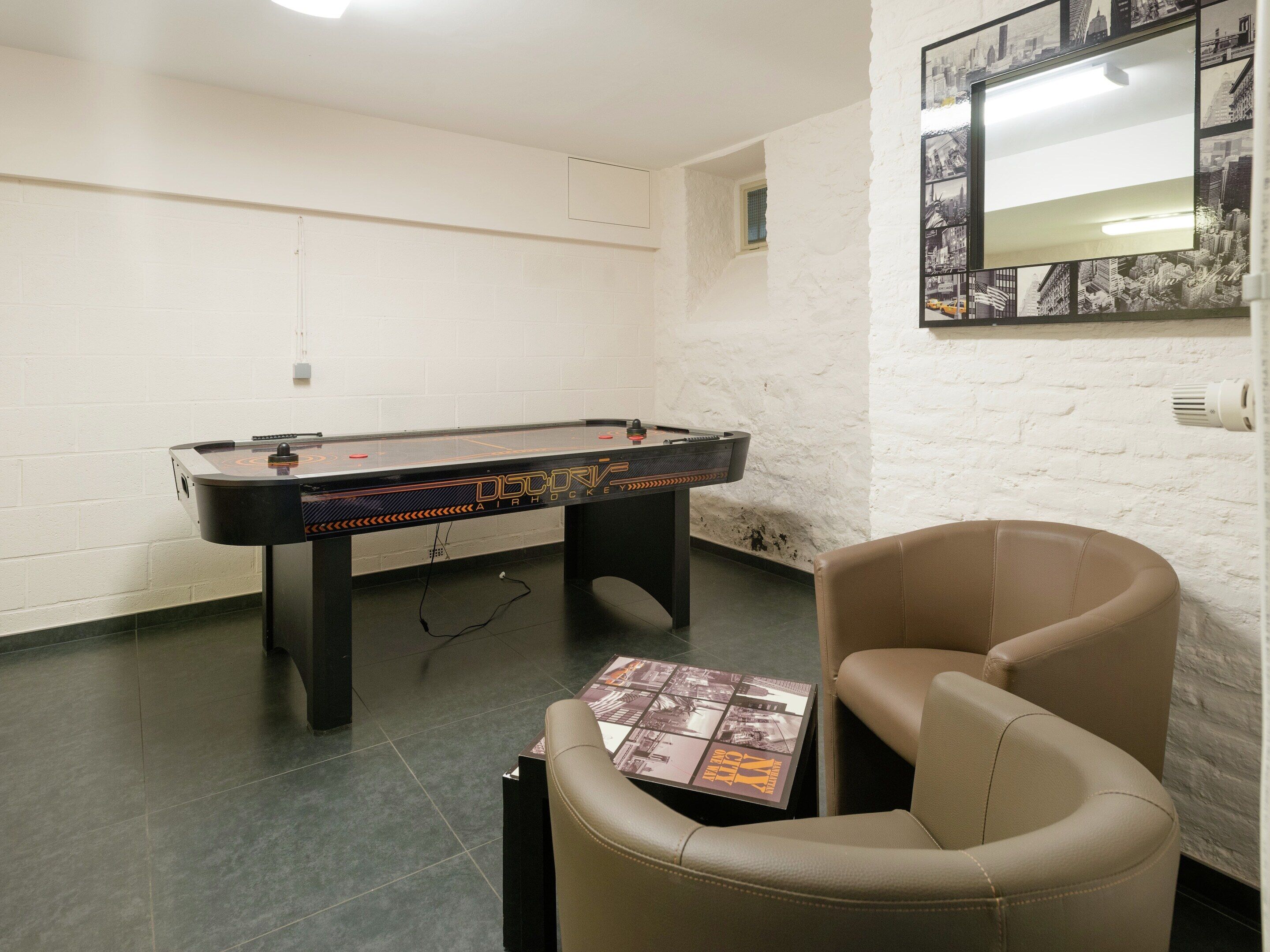 A room with a foosball table, a leather chair, and a wall-mounted mirror.