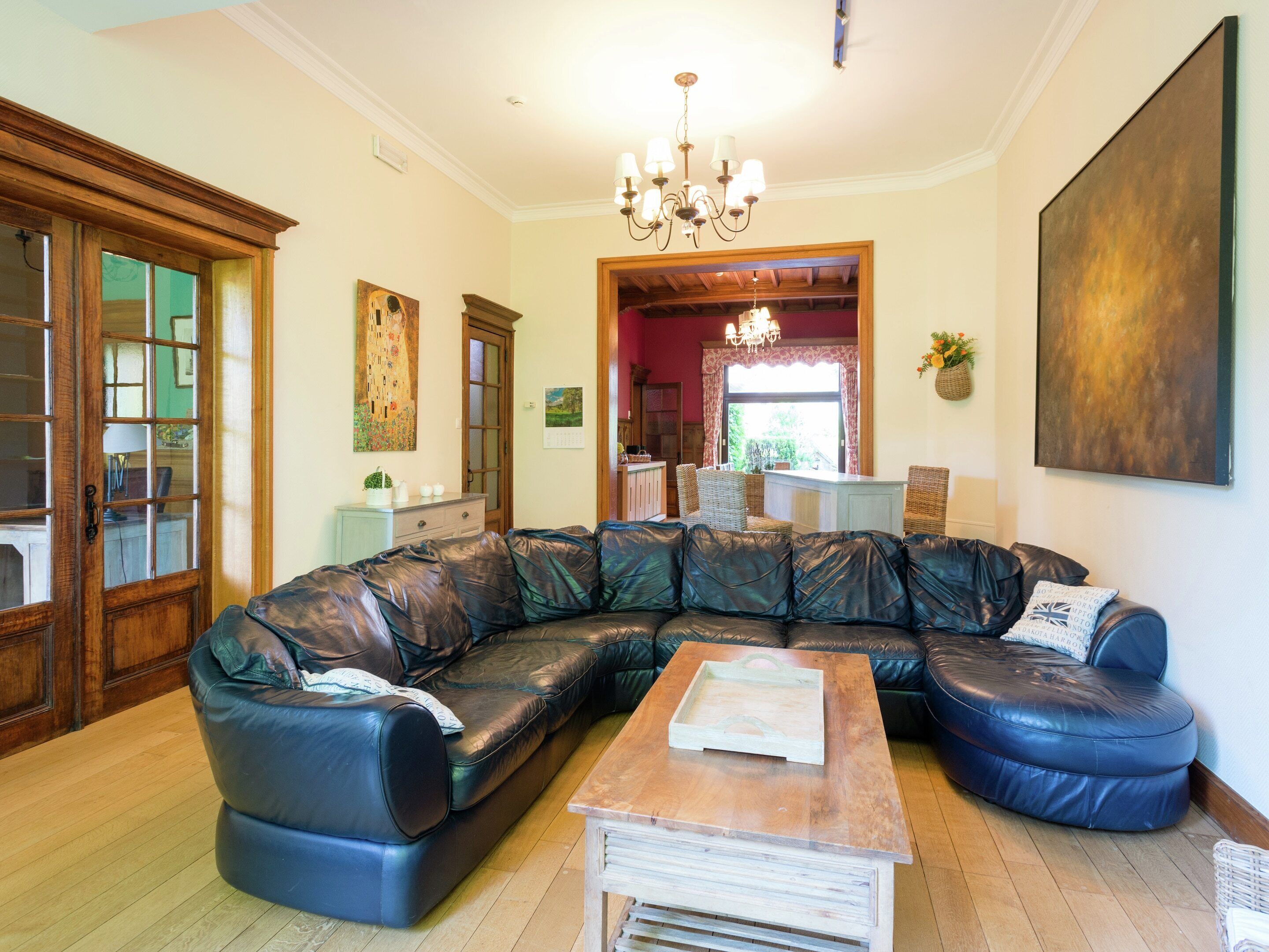 A living room with a large L-shaped sectional sofa, a wooden coffee table, and a chandelier.