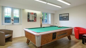 A pool table in a room with wooden flooring, a red chair, and a framed picture on the wall. - Captivating Holiday Home in Malmedy With Sauna (Malmedy)