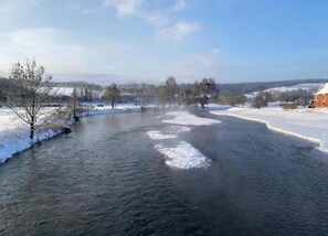 A river with ice patches, surrounded by trees and a house on the right. - Holiday Home in Germany With Garden Terrace (Brakel)
