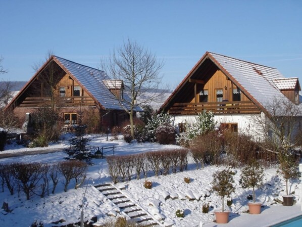 A wooden cabin with a sloped roof, surrounded by snow-covered ground and trees. - Holiday Home in Germany With Garden Terrace (Brakel)