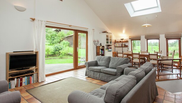 A spacious living area with a television, sofa, and dining table. - Heritage Holiday Home in Roumont (Bertogne)