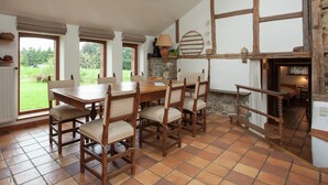 A dining area with a table and chairs, a stone fireplace, and a view of the outdoors. - Heritage Holiday Home in Roumont (Bertogne)