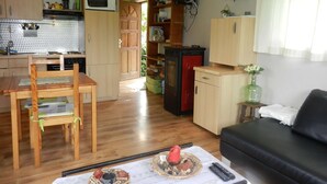A compact living space with a dining area, kitchenette, and a TV mounted on the wall.