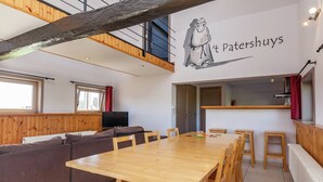 A modern interior with a wooden dining table, brown sofa, and a kitchen area. - Spacious Countryside Farm Stay (Vleteren)