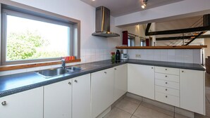 A modern kitchen with a stainless steel sink, white cabinets, and a window providing natural light. - Spacious Countryside Farm Stay (Vleteren)