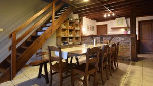 Eine rustikale Küche mit einer Holztreppe, einer Ziegelrückwand und einem Essbereich mit Holztischen und einer Holztischplatte.