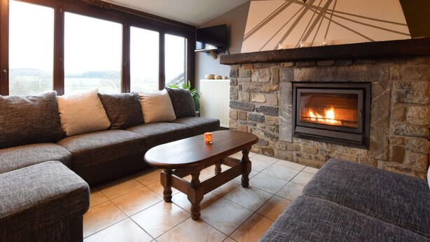 Ein gemütliches Wohnzimmer mit Kamin aus Stein, einem großen Fenster und einem Wanddekor.