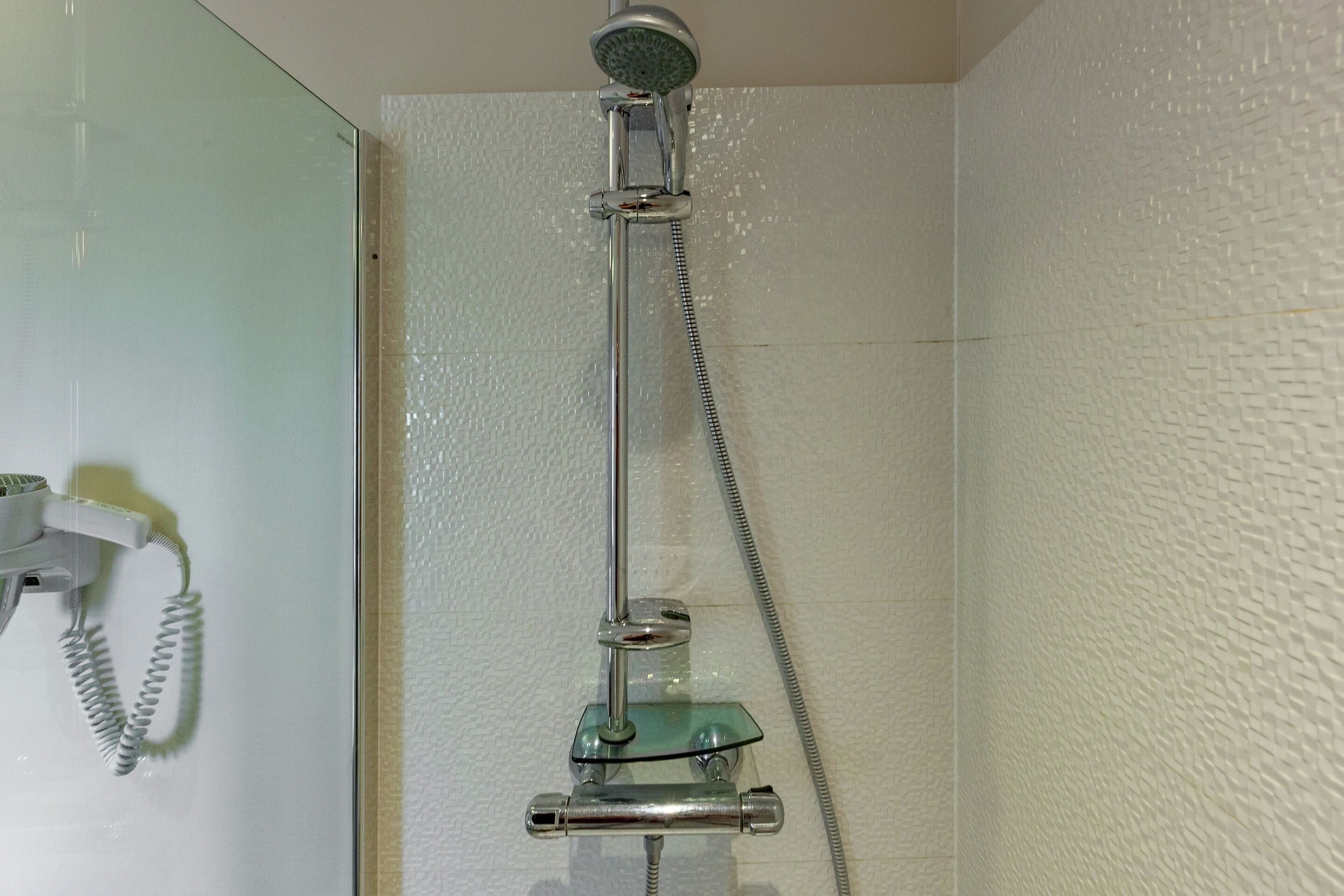 A shower with a handheld showerhead and a handheld faucet.